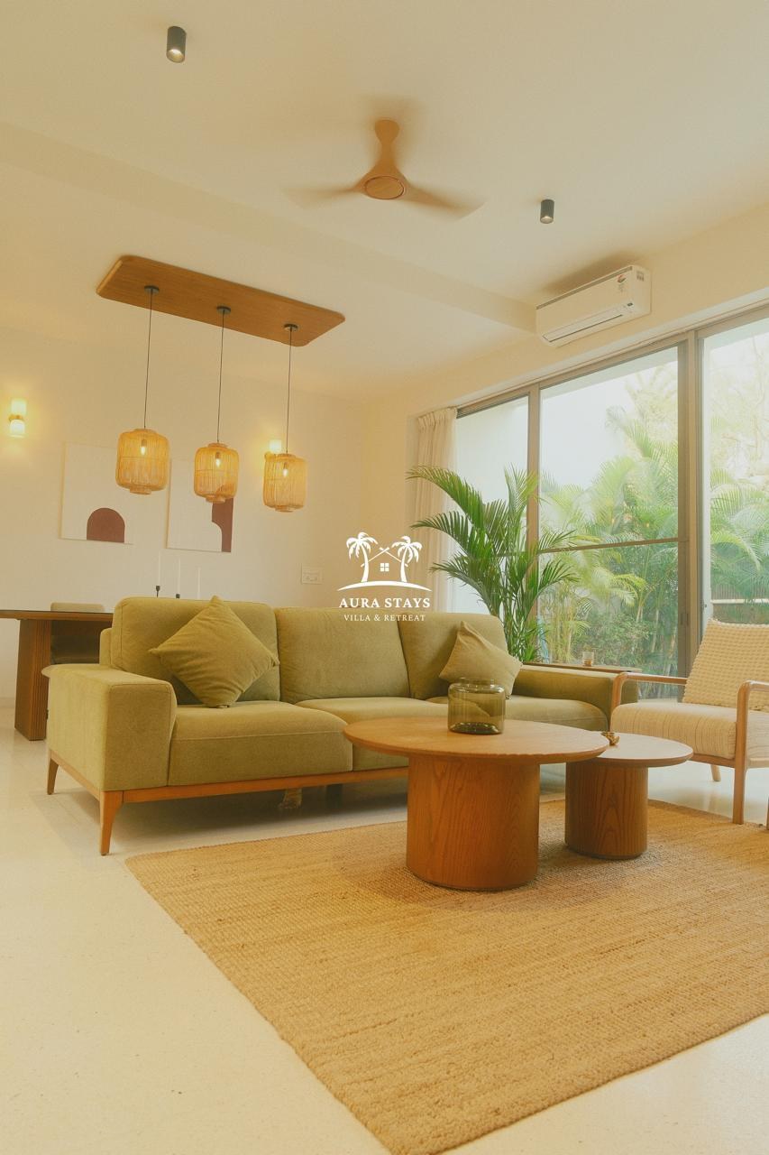 The living room with sofa, timber coffee tables and garden views